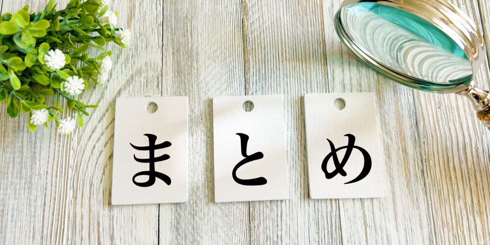白木目テーブルに吊り下げタグ風の3枚に「ま」「と」「め」と1文字ずつ書かれ、脇に拡大鏡と観葉植物が置かれたまとめページイメージ。