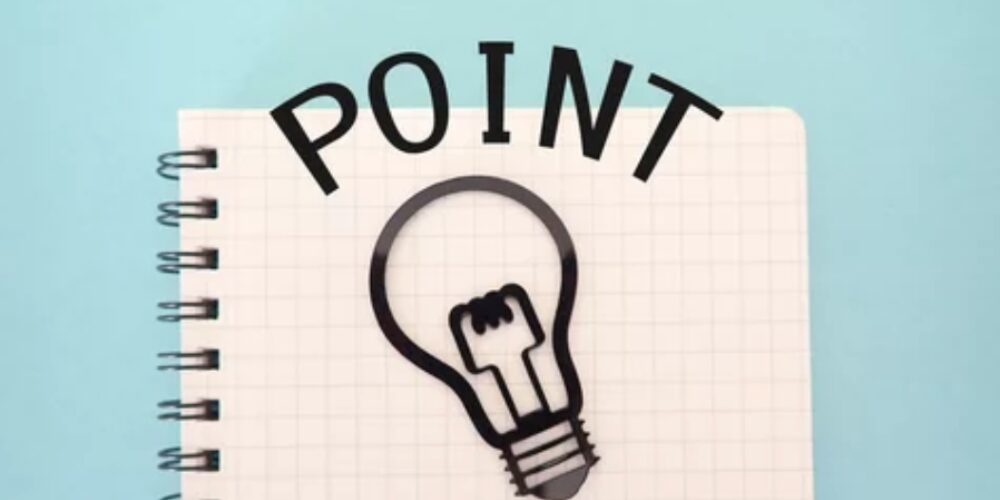 方眼ノートの上に描かれた電球と「POINT」の文字、アイデアを示唆する構成
