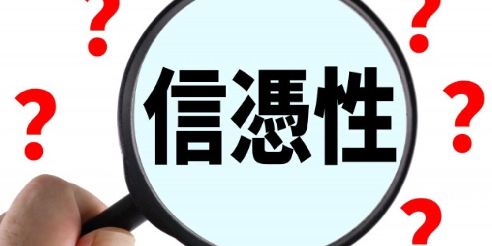 拡大鏡で「信憑性」の文字を強調し、周囲に赤い疑問符が散りばめられている画像