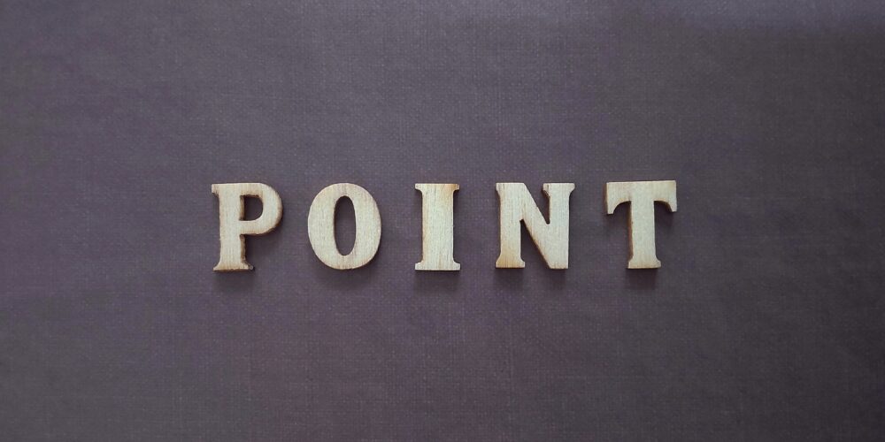 黒い背景の上に木製アルファベットで並べられた「POINT」の文字