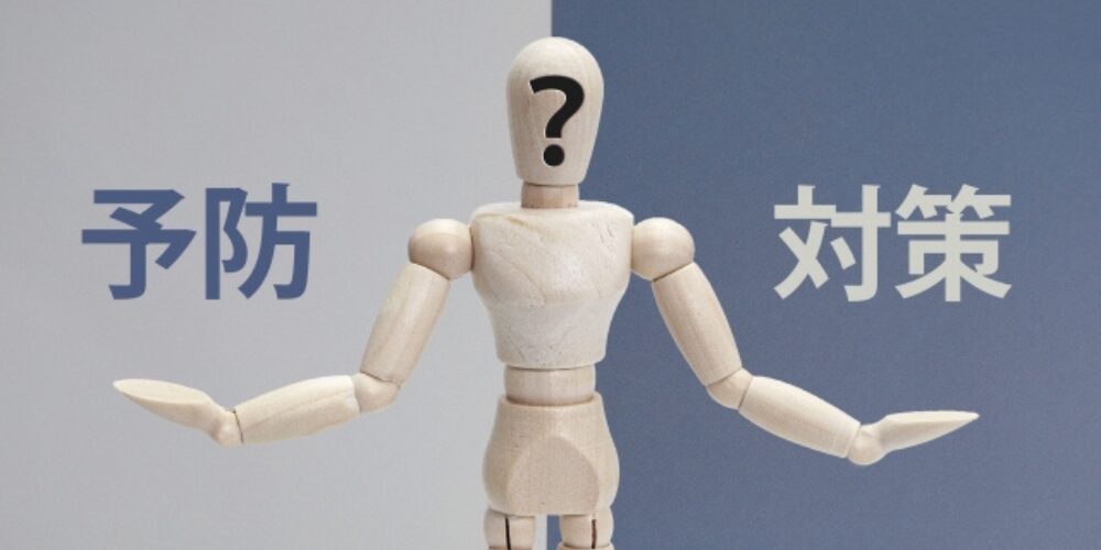 顔にクエスチョンマークが描かれた木製人形が「予防」と「対策」の間で悩んでいる様子