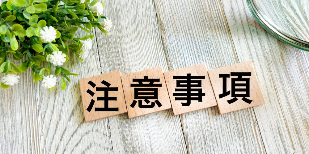 木製タイルを並べて『注意事項』と示し、観葉植物を添えたテーブル上のイメージ