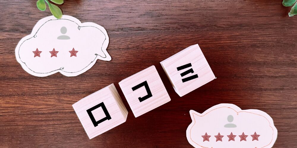 ダークブラウンの木目テーブル上に、星3つのレビューボックスと星5つのレビューボックス、その間に「口コミ」と書かれた木製ブロックが並ぶイメージ写真。