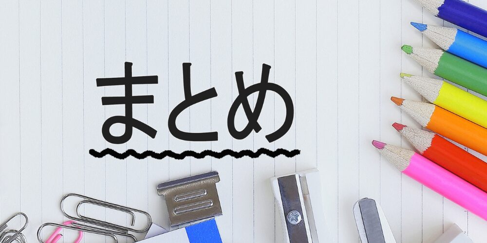 ノートの上に「まとめ」と書かれた文字と、横に並んだ色鉛筆や文房具(クリップ、ホッチキス、鉛筆削り)が置かれている画像