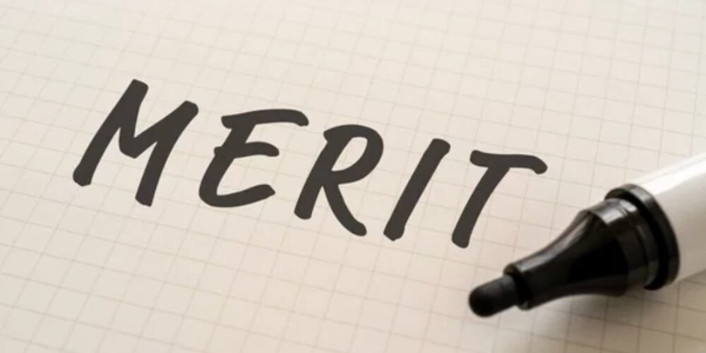 方眼ノートに「MERIT」と書かれた文字と隣に置かれた黒のマーカー