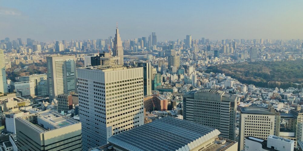 高層ビル群と住宅が広がる都市の街並みを上空から見下ろした景色。