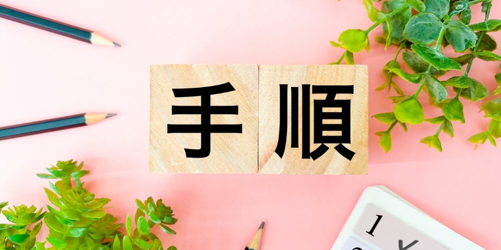 ピンクの背景に観葉植物と電卓を配置し『手順』の木製ブロックを置いた写真