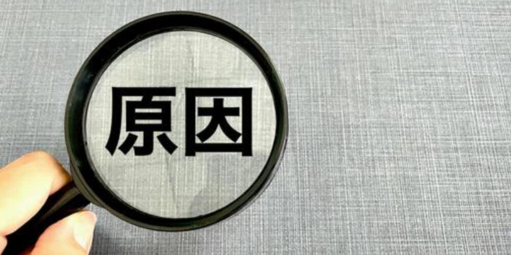 グレーの背景に「原因」と書かれた文字を拡大鏡で拡大している場面