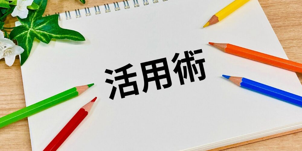 白いノート中央に『活用術』と記し、五色の鉛筆とグリーンを配置した写真