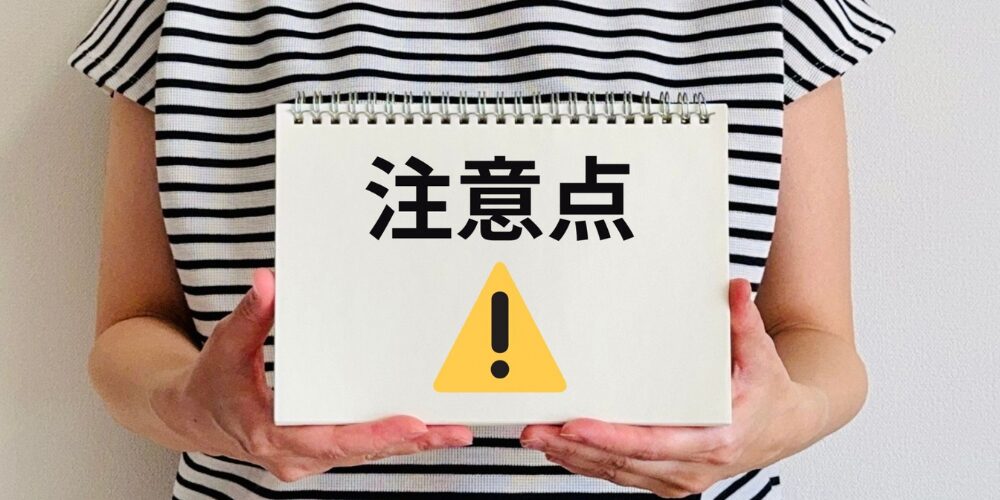 ストライプシャツを着た人物が『注意点』と警告アイコンを示すメモパッドを持つ写真