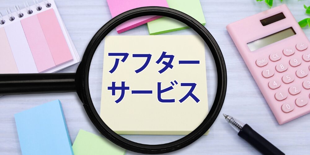 デスク上に置かれた付箋に青文字で「アフターサービス」と書かれ、その付箋を黒い拡大鏡で強調したアフターサービス訴求の写真。
