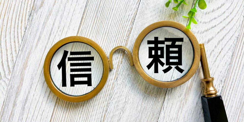 拡大鏡を組み合わせた丸いレンズ部分に「信頼」と書かれているイメージ写真