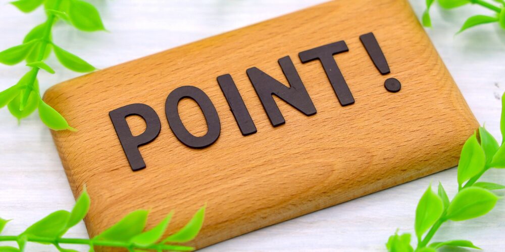 木製プレートに英字『POINT!』が配置され、周囲をグリーンの観葉植物で囲んだポイント提示のイメージ