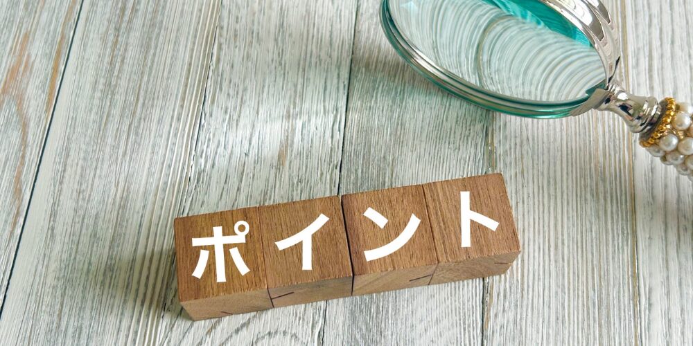 木製テーブルに置いた虫眼鏡と『ポイント』と書かれた木製ブロックのクローズアップ