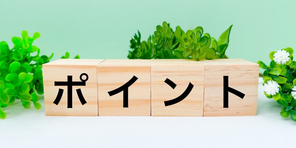 淡いグリーンの背景に観葉植物が配され、手前に「ポイント」と書かれた4つの木製ブロックが横一列に並ぶ写真。
