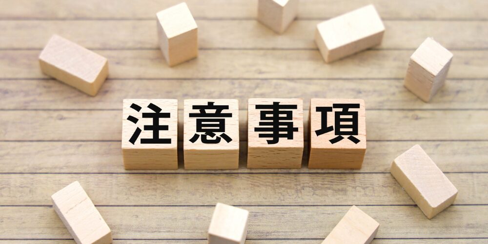 丸太を加工した木製キューブに黒い文字で「注意事項」と書かれ、周囲に余った無地の木片が散らばっている。