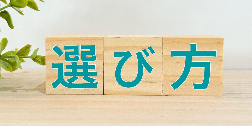  木製の立方体ブロック三つにそれぞれ緑色で「選」「び」「方」と書かれ、ナチュラルな木目と観葉植物が背景。