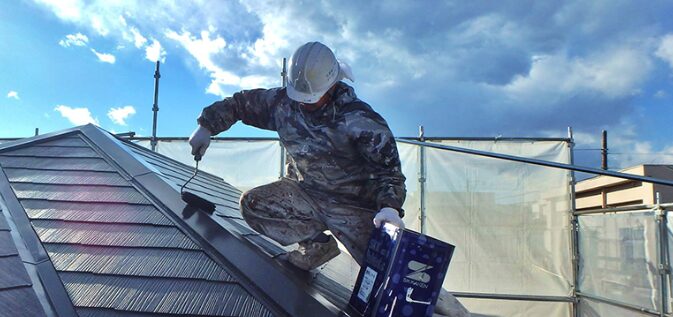 屋根の塗装をしている作業員