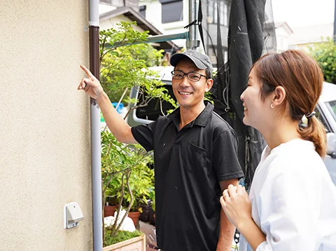 外壁を指さしているスタッフ